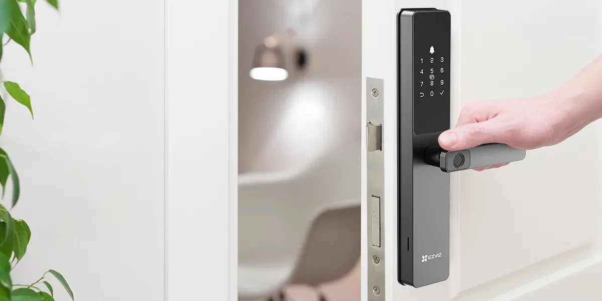 Une main saisit la poignée de la DL05 posée sur une porte blanche, le doigt sur le lecteur d'empreinte