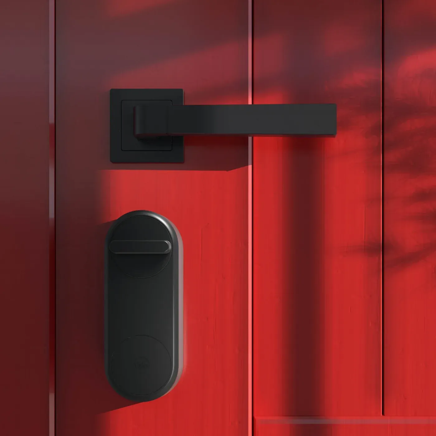 Yale Linus noire posée sous la poignée d'une porte d'entrée rouge